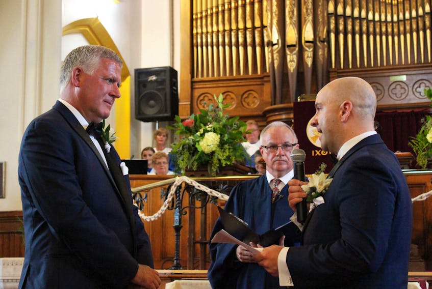 CBRM Mayor Cecil Clarke, left, and his partner Kyle Peterson, of Sydney Mines, recite vows they wrote themselves, while Rev. Stephen Mills looks on during their wedding at the St. Matthew Wesley United Church in North Sydney on Sept. 15.