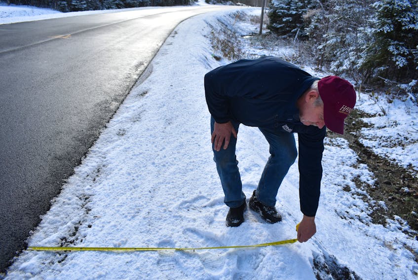 Kevin Hardy measures the shoulder at a part of Hills Road on Nov. 21 to see if it was 1.5 metres wide as required by provincial regulations for a minor collector F series roadway. This spot measured about 0.6 metres.