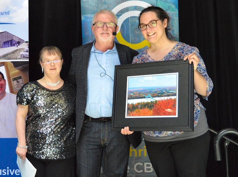 Mark Wafer, centre, receives a photo of the Seal Island bridge from Horizon Achievement Centre client Adele Warner, left, and job coach Leah Noble at Centre 200 in Sydney on Monday. Wafer, a former Tim Hortons franchisee-turned human rights advocate, gave the keynote address during a special luncheon organized by the Cape Breton Regional Chamber of Commerce and the Horizon Achievement Centre as part of National Accessibility Week.
