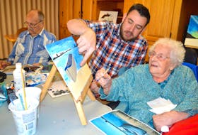 Wil van Hal, middle, recreation director at Maple Hill Manor in New Waterford, assists resident Irmine MacKenzie, 97, as she works on a painting of a boat during a painting group at the manor while resident Mervyn Poole, left, works on a sketch.