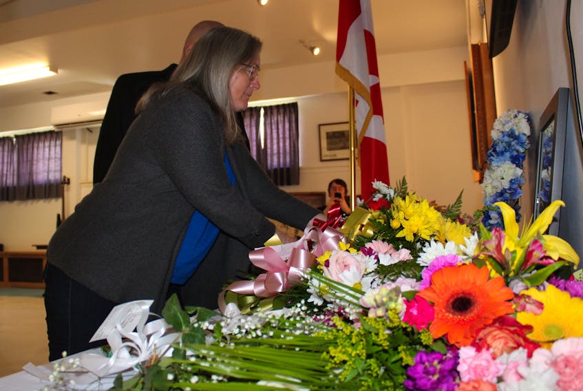 Grace Arsenault from the Canadian Union of Postal Workers lays flowers during the National Day of Mourning ceremonies at the Royal Canadian Legion in Whitney Pier on Sunday.