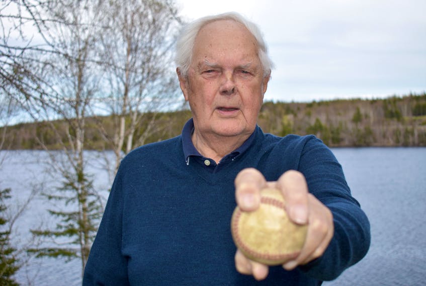 Rev. Ralph Johnston holds a baseball in the back yard of his Marion Bridge home. The 84-year-old retired United Church minister played various sports growing up and was a star baseball player. He will be inducted into the Cape Breton Sports Hall of Fame on Saturday.