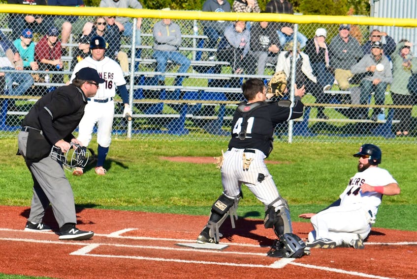 The Sydney Sooners’ Josh Forrest slides into home plate as catcher Dartmouth Moosehead Dry catcher Dan Comeau prepares to catch the incoming throw as Cory Christie, number 16, looks on during third inning play in Game 5 of the Nova Scotia Senior Baseball League championship series on Sunday afternoon at Susan McEachern Memorial Ballpark in Sydney.