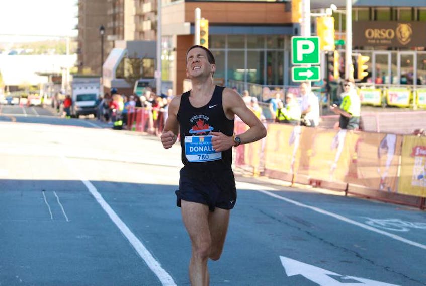 Donald Rasmussen of Antigonish crosses the finish line first after running in the half-marathon at the Scotiabank Bluenose Marathon on Sunday.