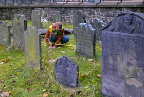 Saint Mary’s archeological student Katherine Lutz places a marker that will be used as a group of archeologists begin marking out a section to be mapped in the Old Burying Ground in Halifax on Saturday.