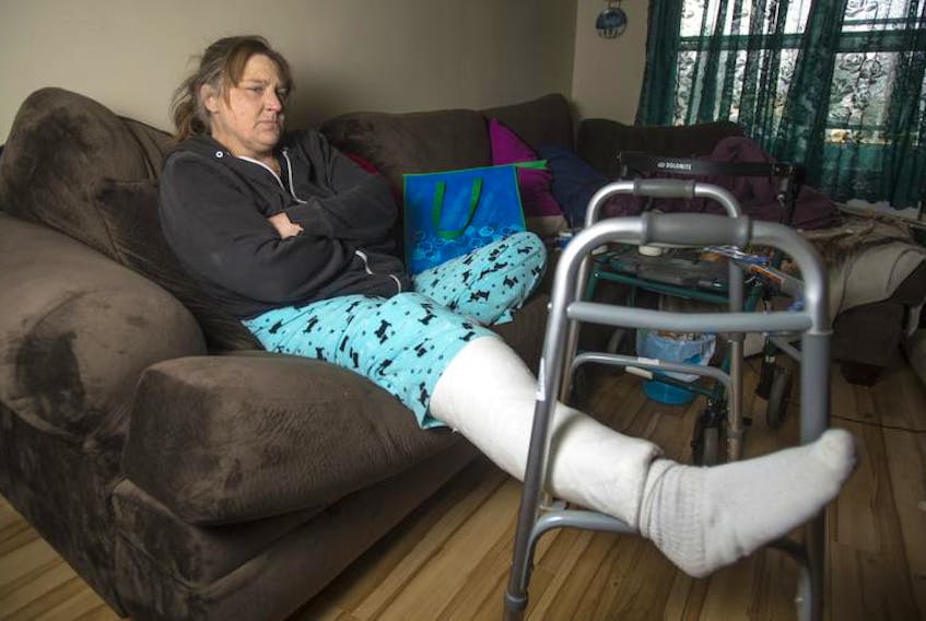 Christine Dodge sits on the couch in her Dartmouth apartment on Friday afternoon. Dodge broke her knee after she slipped on ice earlier this month. She was treated at the hospital and was sent home that night. Dodge wanted to stay at the hospital since she needs dialysis three times a week but was not allowed to do so.