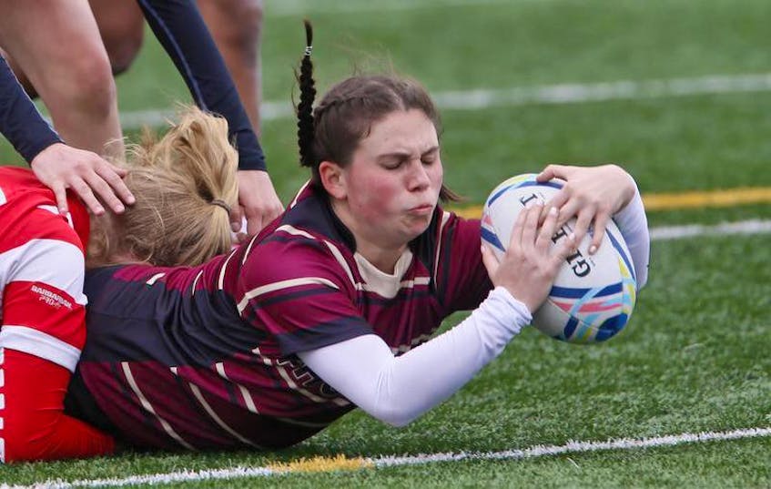 Citadel’s Kathleen Dolan is tackled as she scores a try against Halifax West during metro high school girls’ rugby action on Mainland Common on Thursday. The Phoenix defeated the Warriors 48-12.