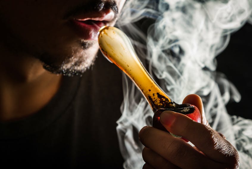 A man uses a pipe to smoke marijuana.