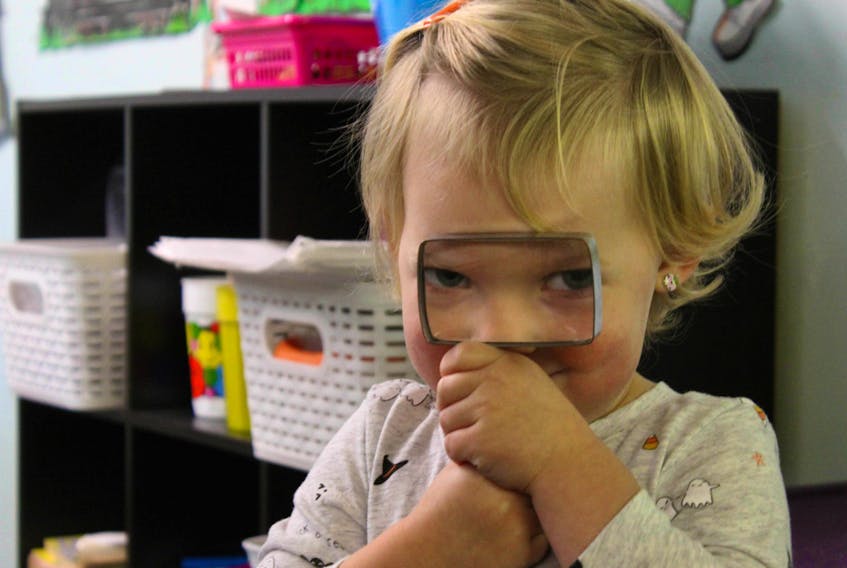 Emersyn Brown looks through a magnifying glass at Wee Folk Kindergarten in Kentville Thursday. The 49-year-old business is closing next month because of declining enrollment after pre-primary programs were instituted across the province.
