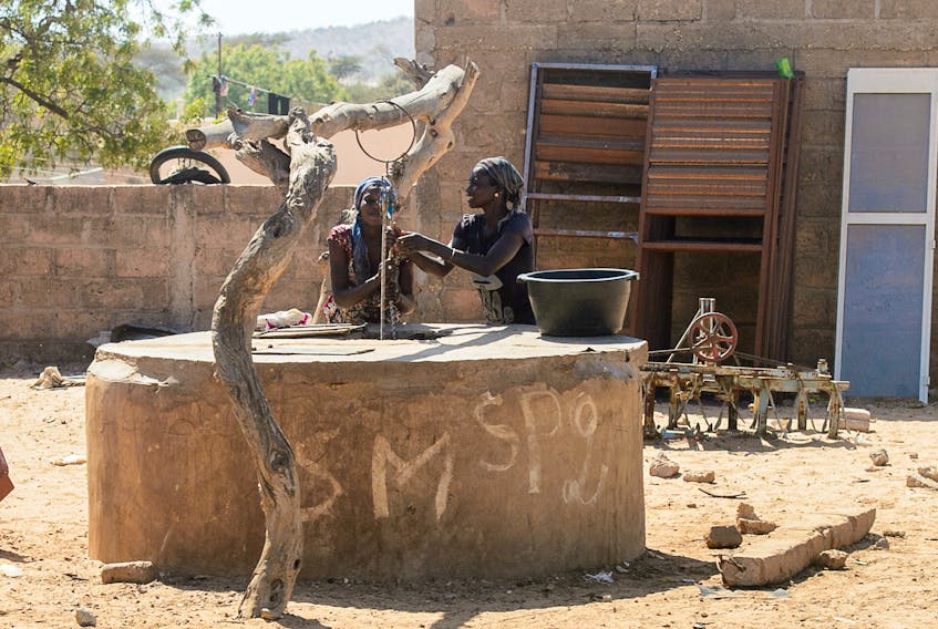 Two women draw water from a well in Senegal. A significant decline in rainfall has made water collection, a typically female job in that country, into a much more labour-intensive process.