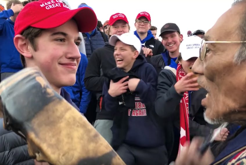 The boy who went viral: Nick Sandmann shown here in his MAGA cap with fellow students next to Indigenous elder playing the drum. - Instagram/ka_ya11