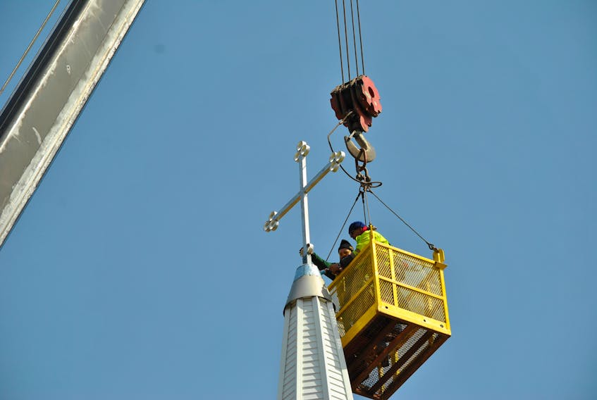 Workers from S.W. Weeks Construction install a new cross on the steeple at Christ Church in Stellarton.