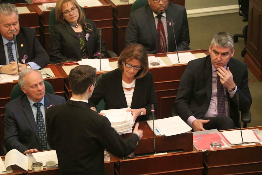 Nova Scotia Finance Minister Karen Casey hands copies of the 2019-20 provincial budget to a page to distribute to MLAs at Province House on Tuesday, March 26, 2019.