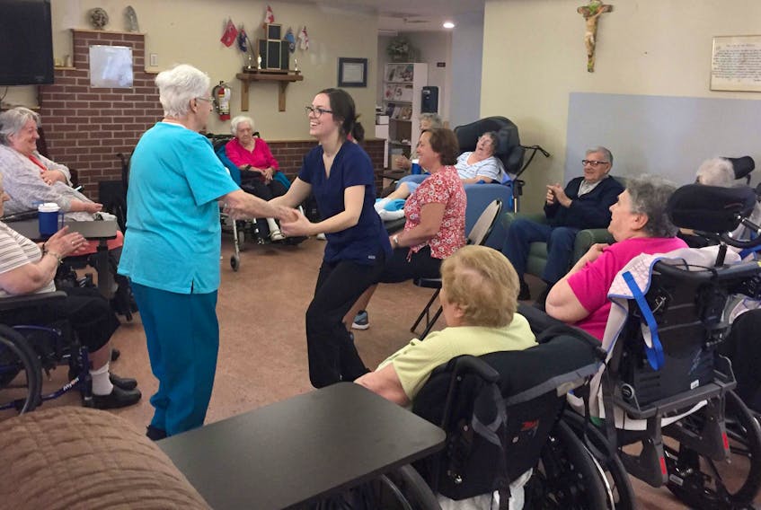 Licensed Practical Nurse Kelsey Matthews dances with a resident of the St. Anne Centre during morning exercise activities.