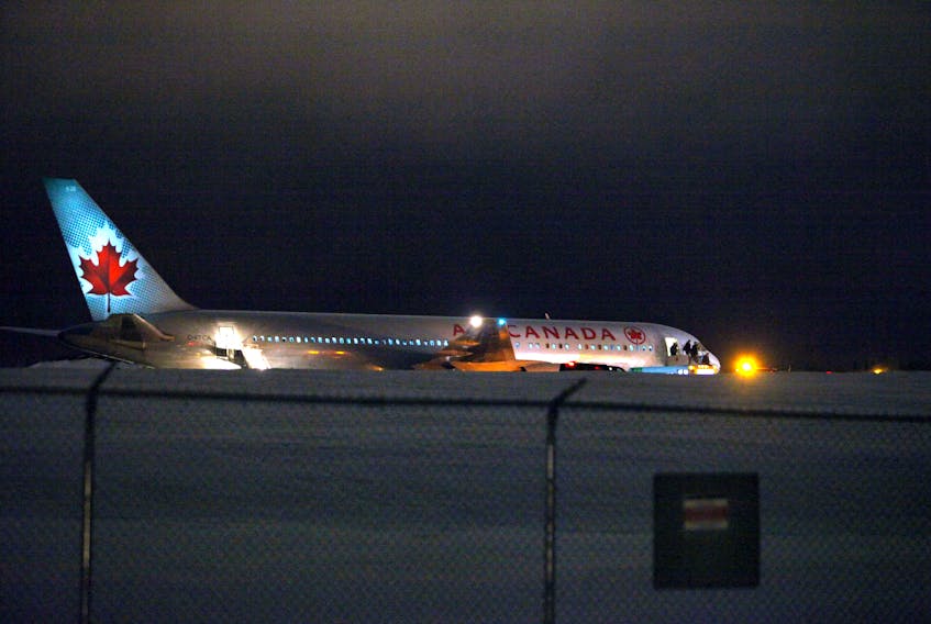 Passengers and crew disembark from an Air Canada Boeing 767 stuck halfway down the main runway at Halifax Stanfield International Airport on Monday night, March 4, 2019. The airport authority says Flight 614 from Toronto landed on Runway 23 at about 6:30 p.m. but was "unable to make it to the gate due to poor weather."