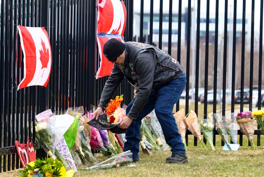 A member of the Veterans Canada motorcycle group leaves a riding bandana at a makeshift memorial to Nova Scotia shooting victims outside the Nova Scotia RCMP headquarters in Burnside Monday afternoon, April 20, 2020.