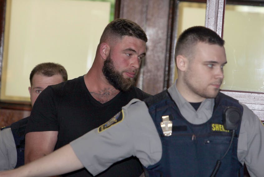 Chris Allen Sampson, a bouncer at Reflections Cabaret in downtown Halifax, is escorted out of provincial court Tuesday after his arraignment on charges of aggravated assault and breaching a recognizance.