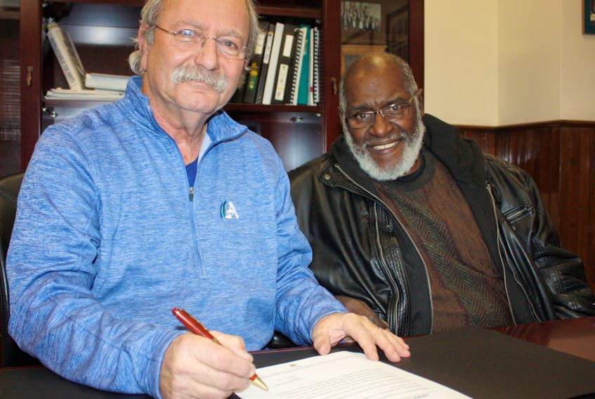 Amherst Mayor David Kogon signs a proclamation declaring February as African Heritage Month in the town while Cumberland African Nova Scotian Association chairman Brian Martin looks on.