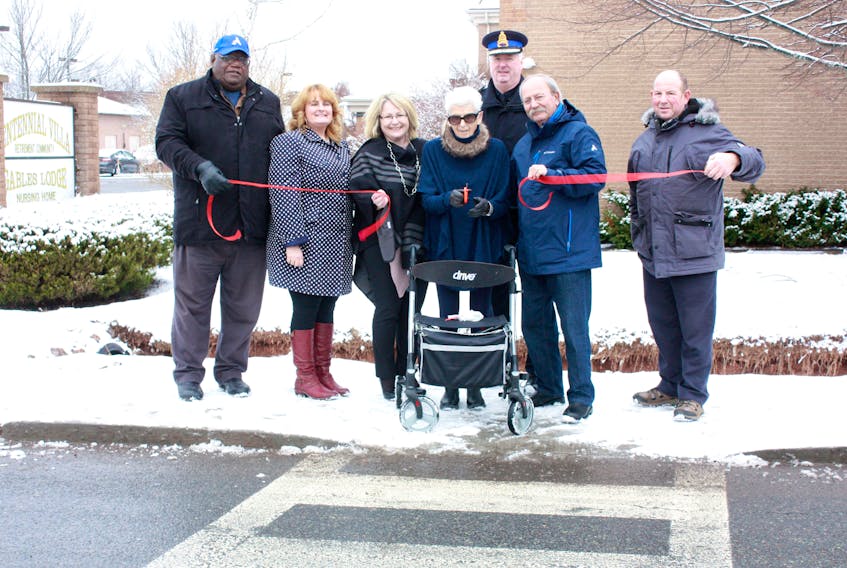Centennial Villa resident Pat Skinner cut a ribbon Dec. 12 to officially open the new crosswalk on Church Street in Amherst. She was assisted by Coun. Darrell Jones, Centennial Villa administrator Susan Collins, Deputy Mayor Sheila Christie, Police Chief Ian Naylor, Mayor David Kogon and Coun. Terry Rhindress.