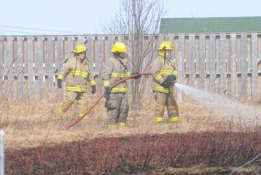 Firefighters apply pressure to hot spots resulting from a Wednesday morning brush fire on the south side of Carbonear.
