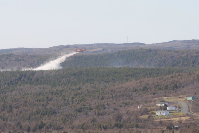 A provincial government waterbomber dumps a load on a fire burning near Victoria.