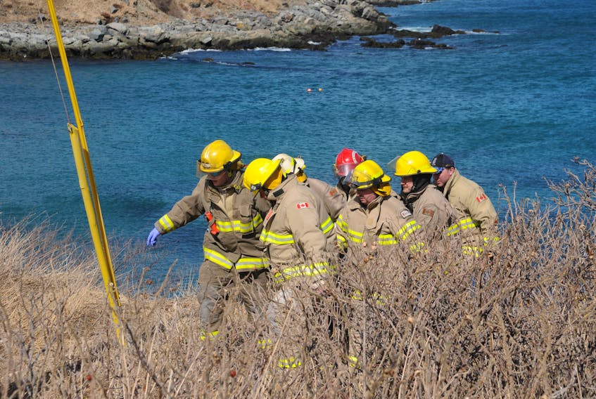 Firefighters carry a woman on a stretcher leaving the beach in Crocker’s Cove, Carbonear.