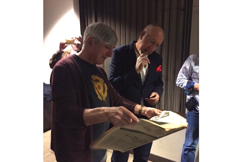 George Robinson, left, shows rock legend Pete Townshend a copy of a 1974 edition of the New Musical Express with a feature article on a school production of The Who's rock-opera "Tommy" Robinson handled the music for.