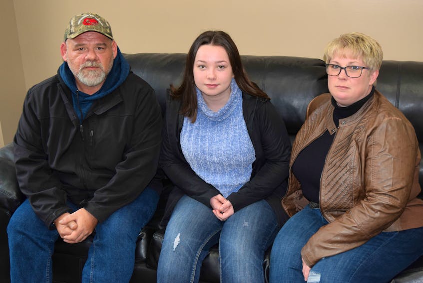 Abby Falconer, centre, suffered a concussion after being hit with a binder on a bus last year. Her parents Travis and Kelly Falconer, shown, wish that the incident had been taken more seriously from the start.