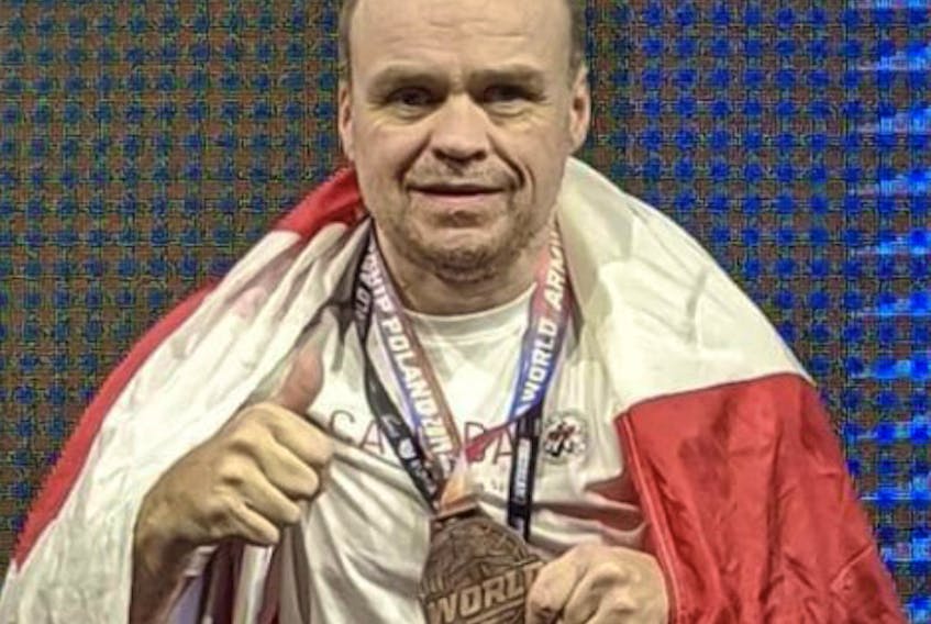While draped in the Canadian flag, Garry Kell shows off the bronze medal he just won at the International Federation of Armwrestling World Championships in Rumia, Poland. CONTRIBUTED