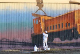 Winnipeg-based artist Charlie Johnston (also known as C5) works on a mural on the side of the paper shed in Botwood Aug. 28. The football-field length work is expected to be the largest mural in Newfoundland and Labrador upon completion.