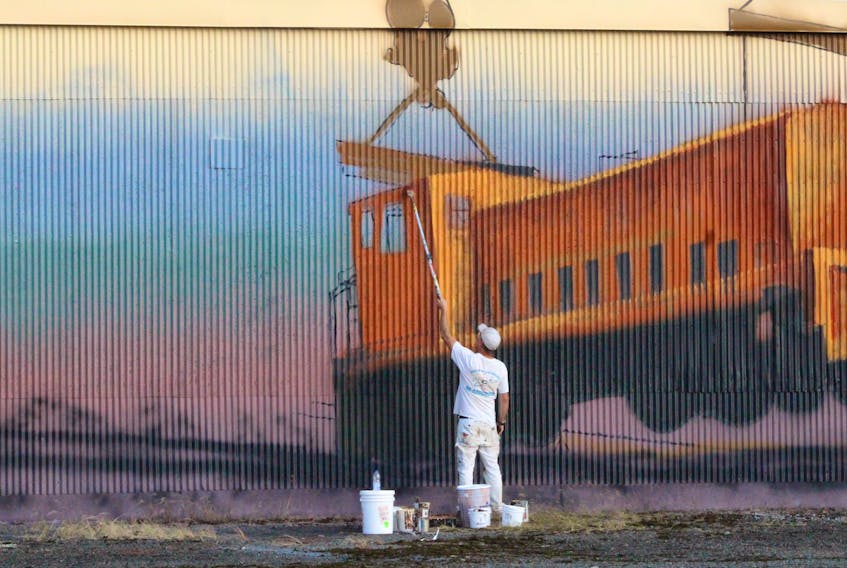 Winnipeg-based artist Charlie Johnston (also known as C5) works on a mural on the side of the paper shed in Botwood Aug. 28. The football-field length work is expected to be the largest mural in Newfoundland and Labrador upon completion.