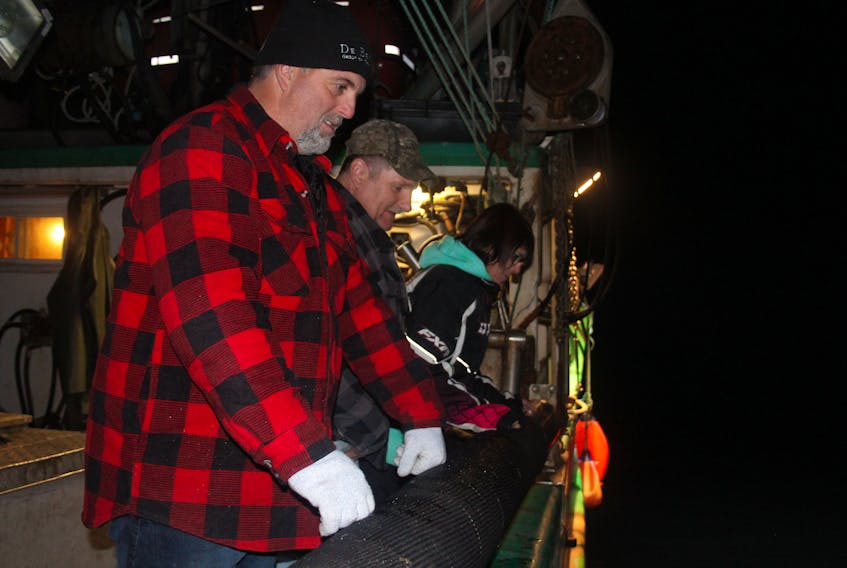 Crewmembers, from left, Hayward Mitchell, Brian Osmond and Jackie Roberts can’t help but get caught up in the large amounts of mackerel being drawn to the surface, so close to the shores of Robert’s Arm the evening of Oct. 17.