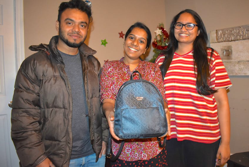 Akhil Satheesan, from left, Rose Mathew and Alina Jordy, all university students from Kerala, India, pose for a photo in a southend Sydney apartment this week. Mathew is holding the backpack that contained her rent money — $800 — when she lost it Saturday. Luckily, local resident Jean Grisdale found it in a snowbank and returned it to her. Chris Connors/Cape Breton Post



