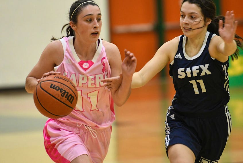 Mackenzee Ryan of the Cape Breton Capers women's basketball team, left, carries the ball as Lucia MacKay of the St. Francis Xavier X-Women follows during Atlantic University Sport action at Sullivan Field House in Sydney on Thursday. Cape Breton won the game 104-76.