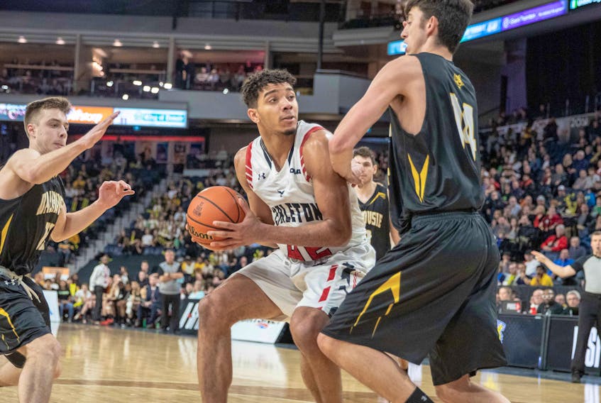 Eddie Ekiyor of the Carleton Ravens is defended by Dalhousie's Sascha Kappos and Keevan Veinot (left) during the U Sports Final 8 basketball semifinal Saturday at Scotiabank Centre. - VALERIE WUTTI