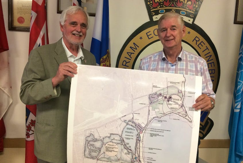 Cyril Aker, president of the Atlantic Memorial Park Society, left, and project planning director, Brian Ferguson, hold a map of the planned Atlantic Memorial Park development following a funding announcement in Sydney Mines Wednesday. Canadian Heritage will contribute $390,000 to the first phase of the project, which aims to restore the command post of the historic Chapel Point Battery.