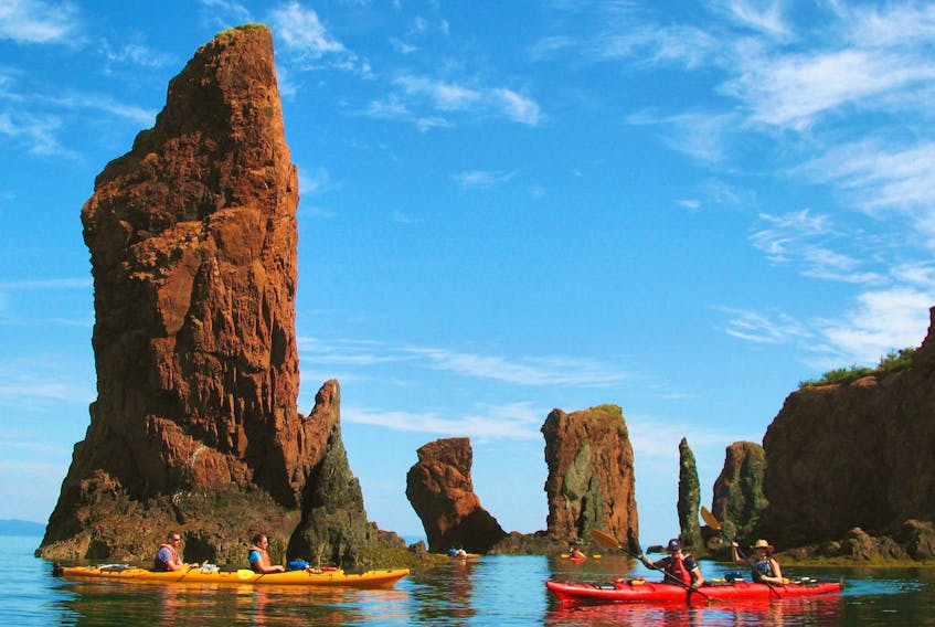 Kayakers with NovaShores Sea Kayaking pass the iconic Three Sisters sea stacks formation in Cape Chignecto Provincial Park.