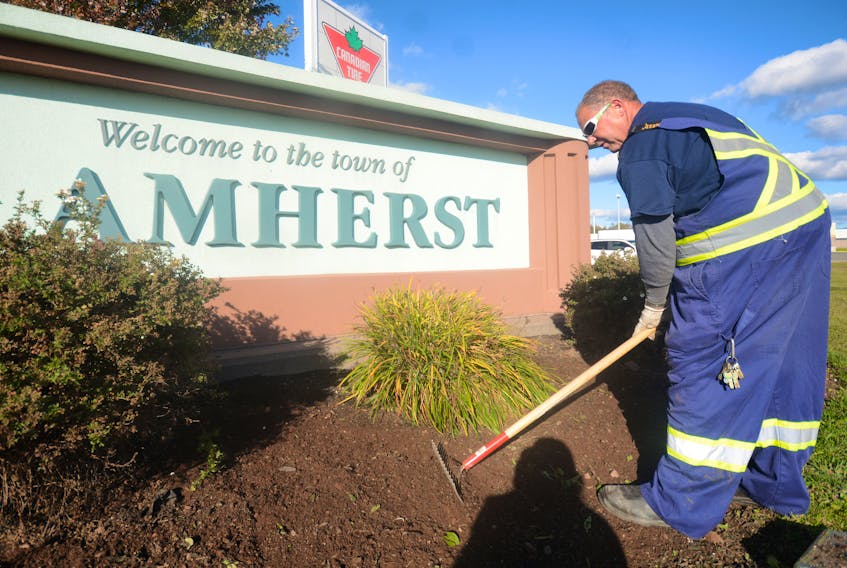 After pulling annual flowers out of the ground, which will be stored away until next spring, Vaughn Martin, an employee with the Town of Amherst, rakes the flower bed at the entrance to Amherst.