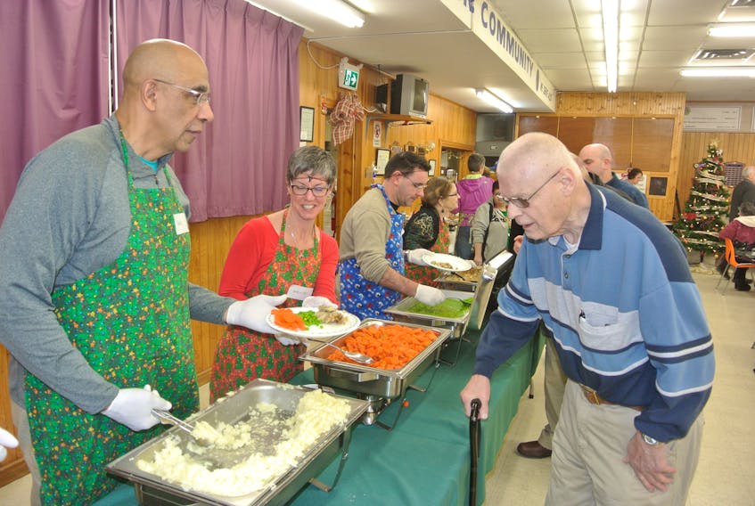 Hal Davidson and Shelley Carroll prepare a plate of food for a participant at Amherst’s Community Christmas Dinner at the Amherst Lions Club on Christmas Day.