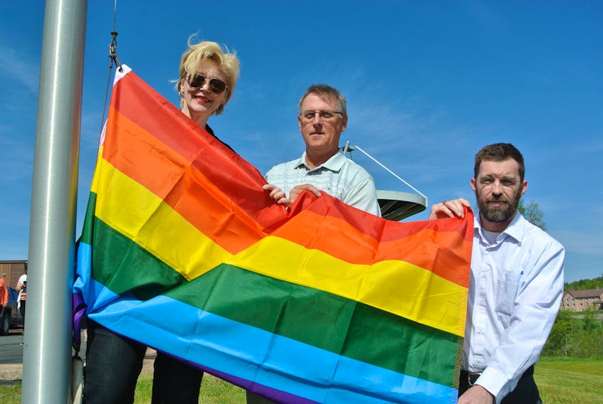 Cumberland North MLA Elizabeth Smith-McCrossin, Cumberland County Deputy Warden Joe vanVulpen and Brent Noiles from Cumberland Pride hold up the Pride flag before its raised during a flag-raising ceremony at the E.D. Fullerton Municipal Building in Upper Nappan on Tuesday.