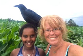 Konjo, a crow, is shown with Maya Mundle and her mother, Jill. Konjo was euthanized by a Lands and Forestry officer on Tuesday. Jill Mundle photo