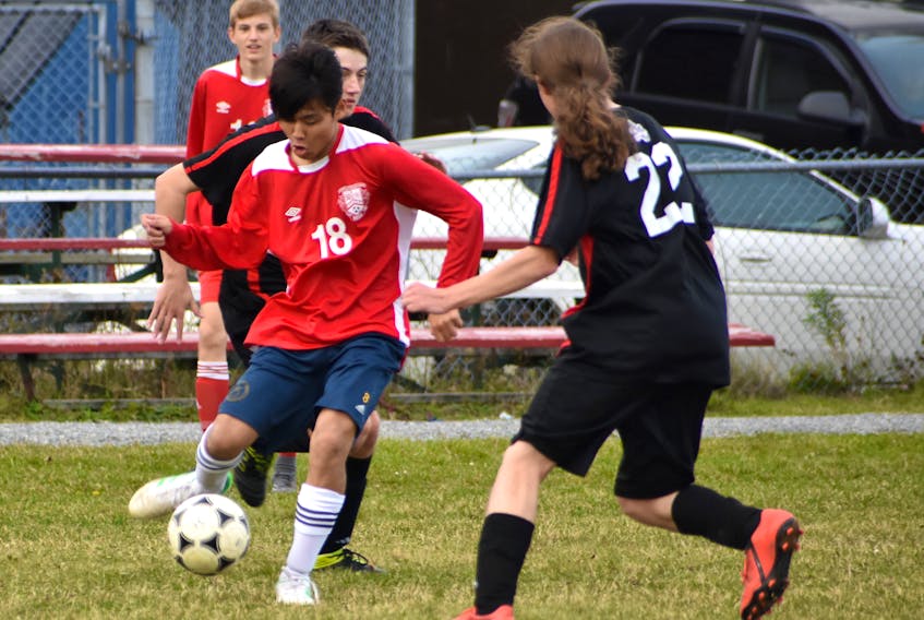 Ayunu Matsumoto of the Riverview Reds, left, prepares to make a pass while Matthew MacIntosh of the Glace Bay Panthers pressures during Cape Breton High School Soccer League boys action at Riverview High School in Coxheath on Friday. The Reds won the game 7-0.