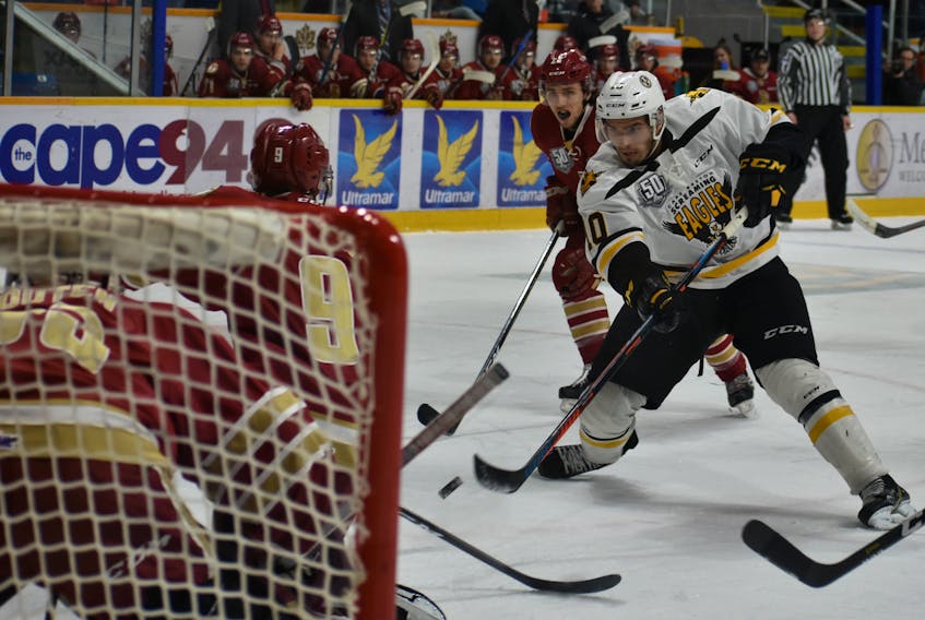 Shawn Boudrias of the Cape Breton Screaming Eagles, middle, fires a shot on goal as Ian Smallwood of the Acadie-Bathurst Titan attempts to block the shot during Quebec Major Junior Hockey League action at Centre 200 on Wednesday. Cape Breton won the game 8-3.