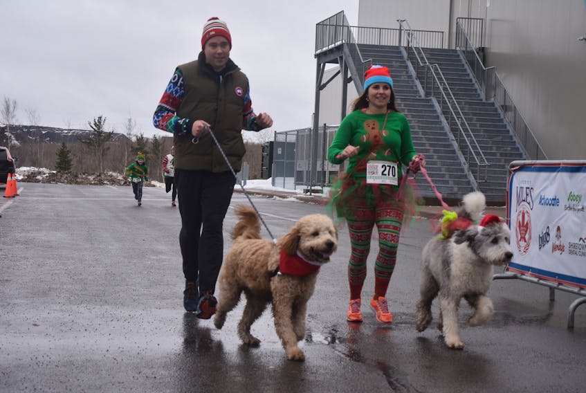 Jonathan Atwin and Amanda Hill cross the finish line with the Tookers the Golden Doodle, and Bizzy the Old English sheepdog.