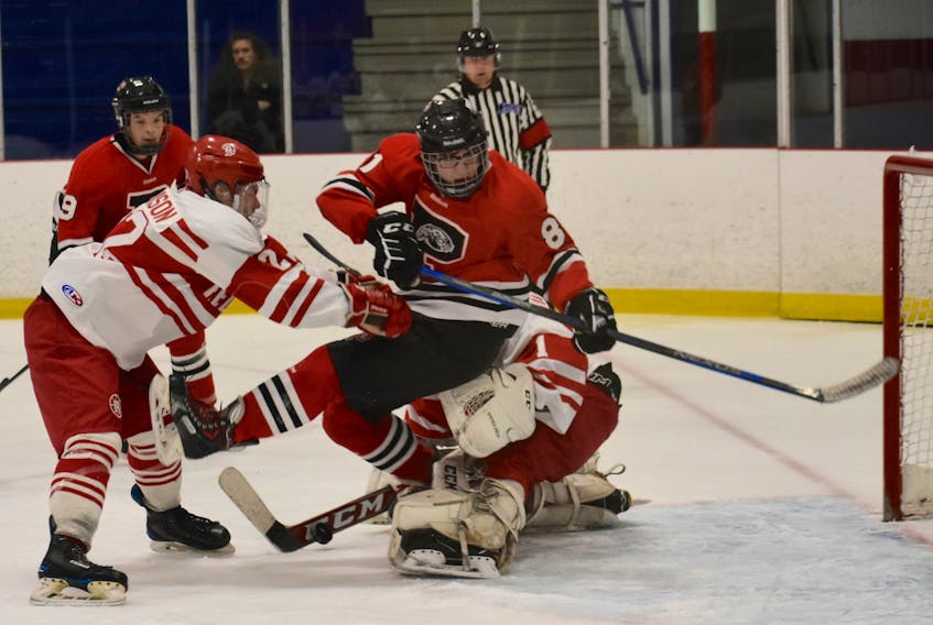 Rory Morrison of the Riverview Redmen, left, pushes Austin Parsons of the Glace Bay Panthers, right, into Redmen netminder Michael MacMullen during Cape Breton High School Hockey League action at the Cape Breton County Recreation Centre on Friday. Riverview won the game 4-3.