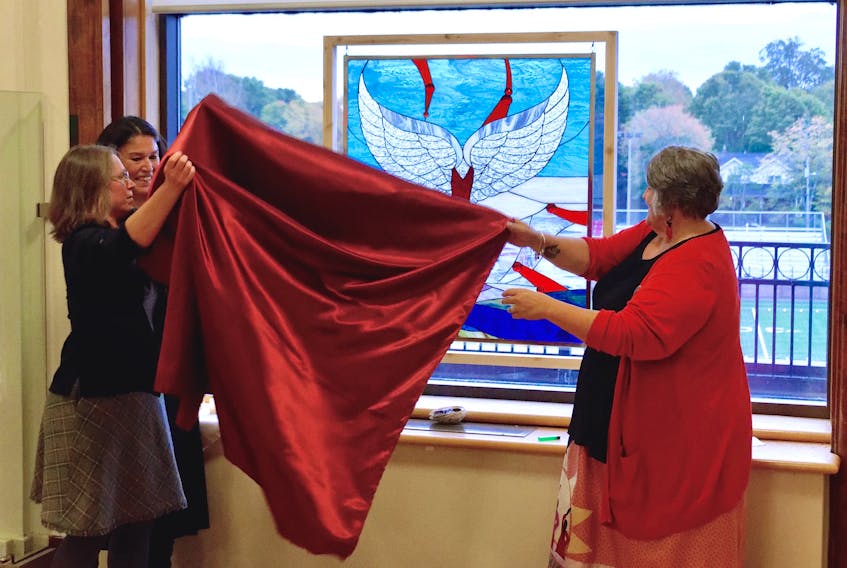 Owens Art Gallery director and curator Emily Falvey, left, Mi’kmaq artist Pauline Young, and Mount Allison’s Indigenous affairs co-ordinator Patty Musgrave-Quinn, right, unveil the commemorative artwork, She Lights the Way, completed by Young, at the university’s Oct. 1 vigil for Missing and Murdered Indigenous Women and Girls.
