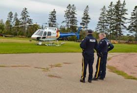 Members of the RCMP discuss the search for two missing boys near Fox Island Friday.
