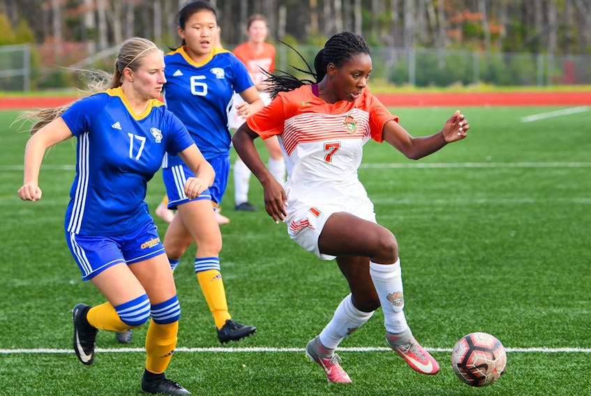 Fatou Ndiaye of the Cape Breton Capers, right, carries the ball while being pressured by Madelaine Leblanc of the Moncton Aigles Bleus during Atlantic University Sport women’s soccer action at the Cape Breton Health Recreation Complex in Sydney. Cape Breton won the game 6-1.