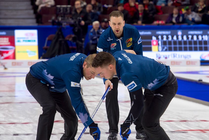Michael Burns/Curling Canada Sweepers Geoff Walker, left, and Brett Gallant go to work on a rock thrown by Brad Gushue, background, during their Roar of the Rings Canadian Olympic Curling Trials game against Brad Jacobs Monday night in Ottawa.