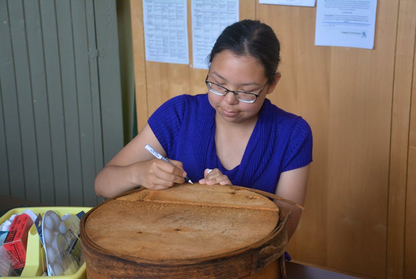 Ayla Kreelac, a student with the Northern Youth Abroad program, labels an old cheese box as part of a work placement at the Antigonish Heritage Museum.